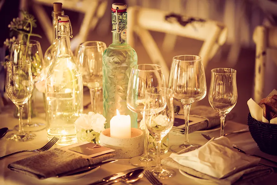 Karaffen und Weingläser stehen auf einem elegant gedeckten Tisch mit Kerzenlicht in warmem Ambiente; daneben ein Brotkorb und Servietten, umgeben von einem unscharfen Hintergrund eines Hotels in Vaterstetten.
